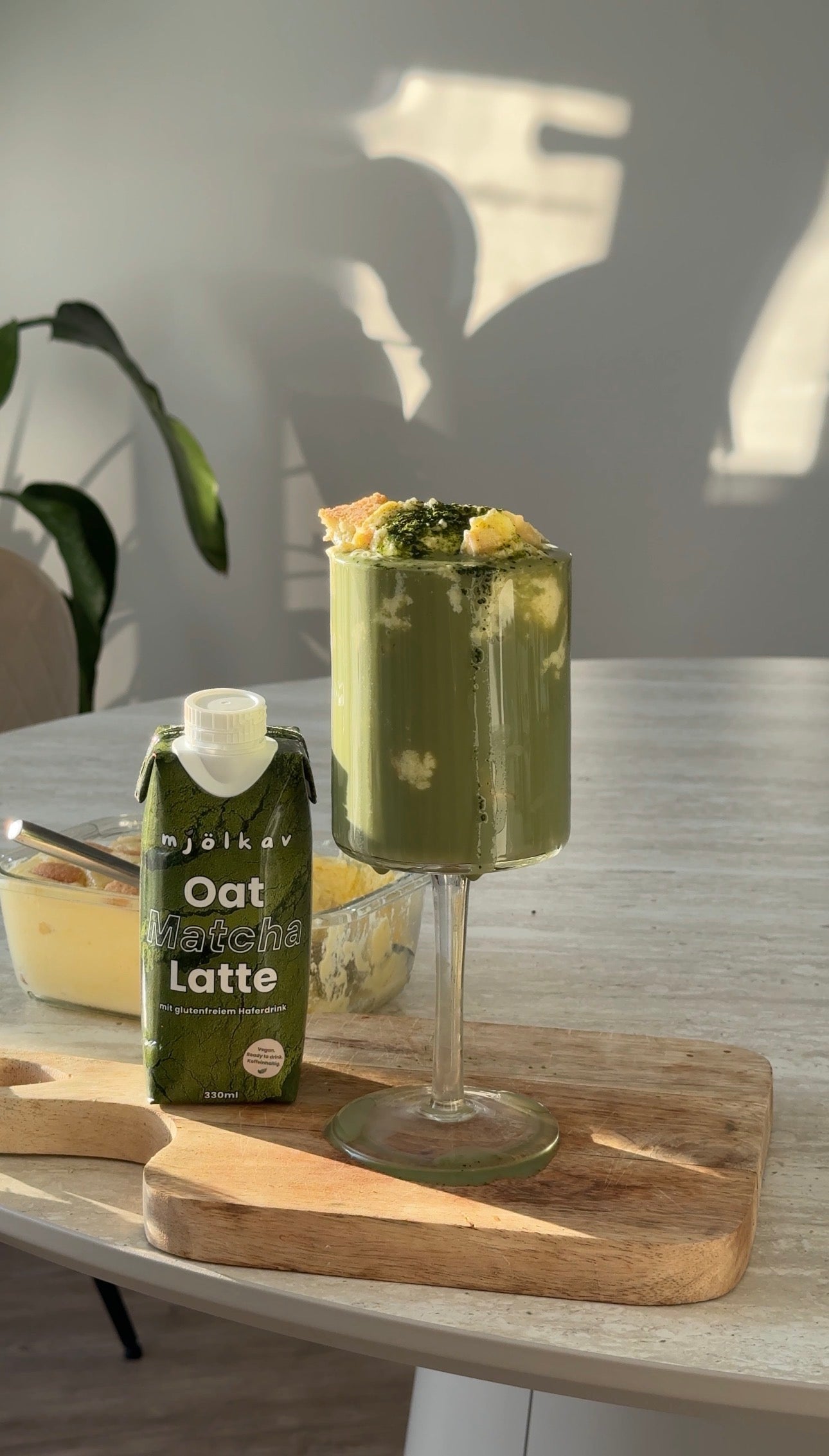 Der perfekte Bananen Pudding Matcha steht auf dem Tisch serviert. Daneben die mjölkav Matcha-Verpackung.