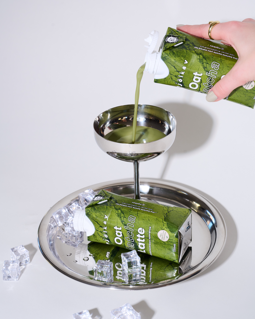 Das Bild zeigt, wie der Matcha Latte in ein Martiniglas edel eingegossen wird.